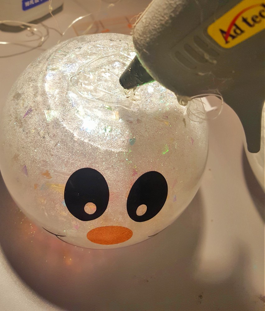applying hot glue to top of snowman