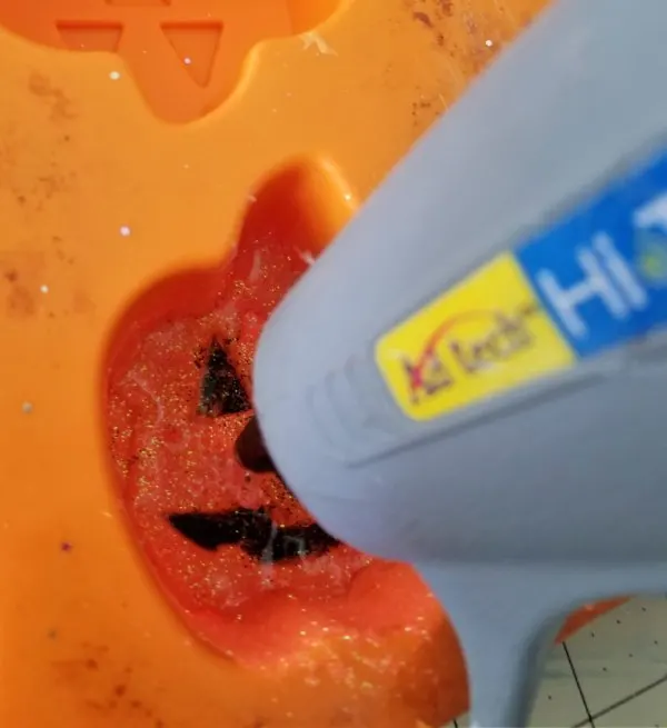 adding hot glue to a silicone mold